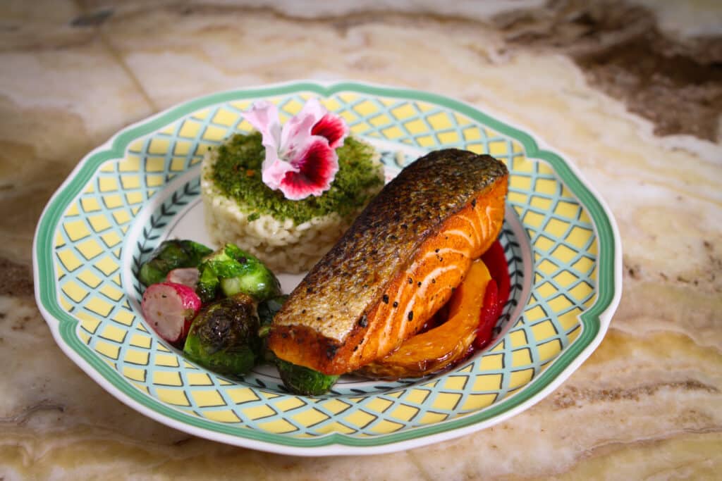 Värikäs lautanen, jossa paistettua lohta, riisiä ja vihreitä ruusukaaleja.